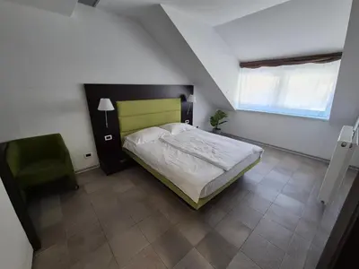 a bedroom with a bed and a green chair at Klass 302 in Kranjska Gora