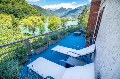 a balcony with tables and chairs and a view of a river at House by the Lake in Most na Soči