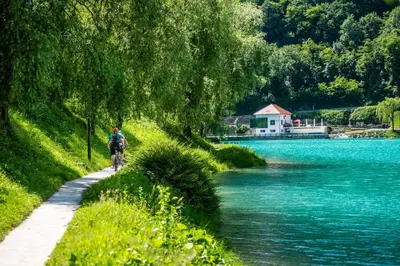 a person riding a bike on a path next to a river at House by the Lake in Most na Soči