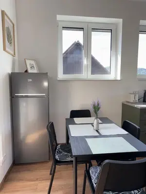 a dining room with a table and a refrigerator at Apartma Amelie & Studio Mimi Bled in Bled