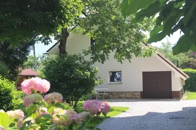 a house with a garage and some pink flowers at Mariana Apartment in Bled