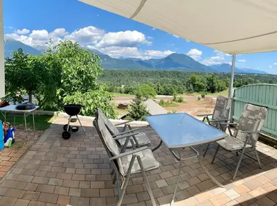 a table and chairs on a patio with mountains in the background at Apartma AS in Bled