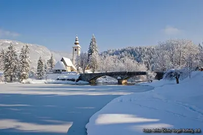 a winter scene with a bridge and a church and snow at Snežak (Snowman) 2 in Bohinj