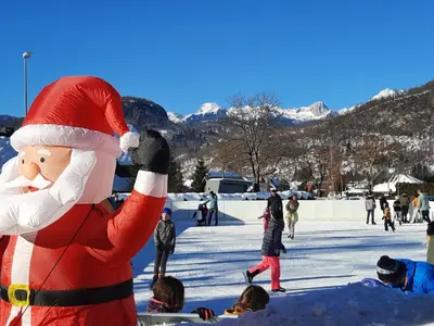 a santa claus mascot standing in the snow at Snežak (Snowman) 2 in Bohinj