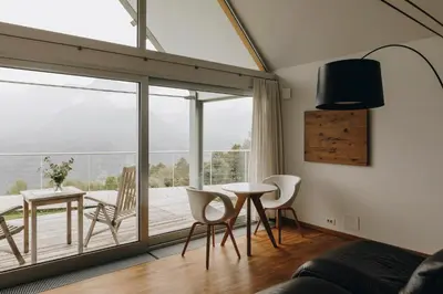 a living room with a table and chairs and a large window at Nebesa Chalets in Kobarid