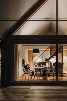 two people sitting at a table in a living room at Nebesa Chalets in Kobarid