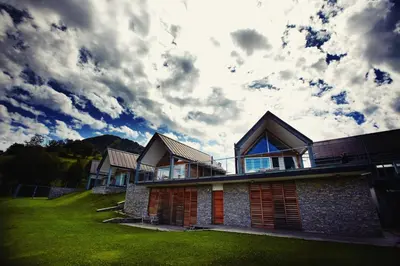 a house on a lawn with a cloudy sky at Nebesa Chalets in Kobarid