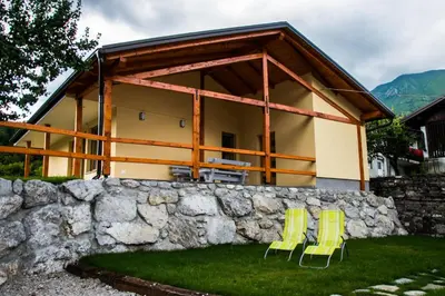 two yellow chairs and a house behind a stone wall at Apartma Fani-Kobarid in Podbela