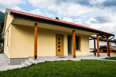 a small yellow house with a red roof at Apartma Fani-Kobarid in Podbela