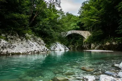 a bridge over a river with clear blue water at Apartma Fani-Kobarid in Podbela