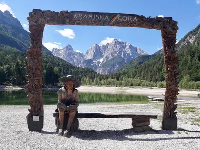a statue sitting on a bench in front of a lake at Apartma BaLe in Kranjska Gora