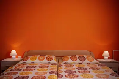 a bed with two pillows and an orange wall at Apartmaji Berginc in Kobarid