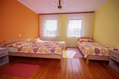 two beds in a room with yellow walls and wooden floors at Apartmaji Berginc in Kobarid