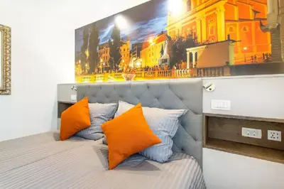 a bed with orange pillows and a painting on the wall at ★ Exclusive Central Apartment ★ FREE Garage ★ in Ljubljana
