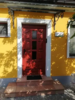 a red door on the side of a yellow house at Apartment Antonia in Dobova