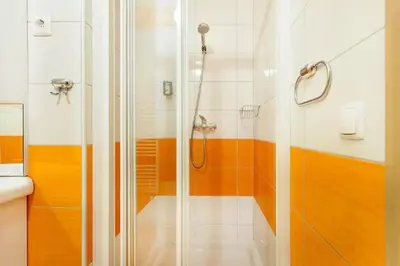 a bathroom with a shower with orange and white stripes at Apartments FABRKA in Ljubljana