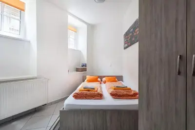 a room with three beds with orange pillows at Apartments FABRKA in Ljubljana
