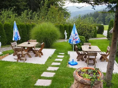 two picnic tables with umbrellas in a garden at Gostilna PIK in Prevalje