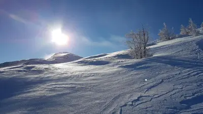 a snow covered slope with the sun in the sky at Gostilna PIK in Prevalje