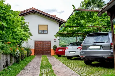 a house with cars parked in the driveway at Sobe Černilogar in Tolmin