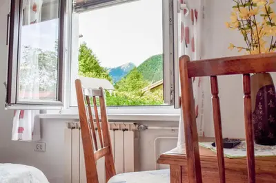 a pair of chairs sitting in front of a window at Sobe Černilogar in Tolmin