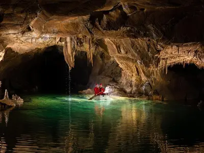 a person in a boat in the water in a cave at Rooms Šajina in Podgrad