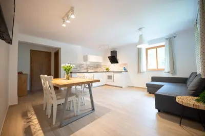 a kitchen and living room with a table and a couch at Hiša Urška in Log pod Mangartom