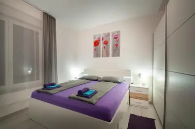a white bedroom with a large bed with purple sheets at Apartment MATEA in Kobarid