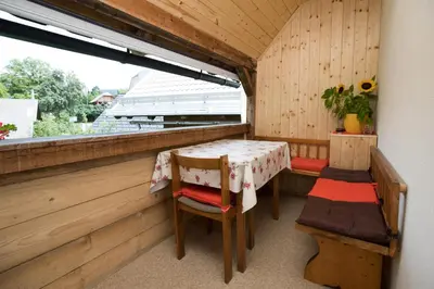 a porch with a table and chairs and a window at Apartments Kocjanc in Bohinj
