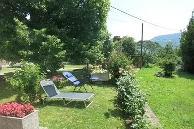 a yard with two chairs and flowers in the grass at Apartma Kapitanovše in Ajdovščina