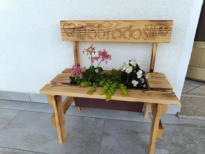 a wooden bench with a flower arrangement on it at Apartma Kapitanovše in Ajdovščina