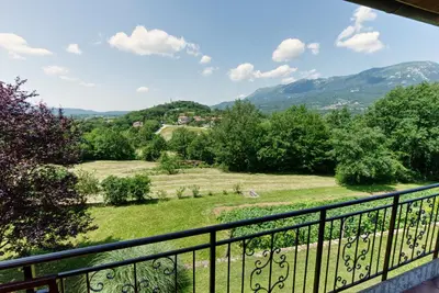 a balcony with a view of a field and mountains at Apartma Kapitanovše in Ajdovščina