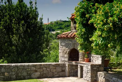 a stone fireplace in a garden with a stone wall at Apartma Kapitanovše in Ajdovščina