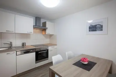 a kitchen with a wooden table and white cabinets at 1861 Blejka apartments Bled in Bled