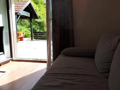 a couch in front of a sliding glass door at House Utrinek with free play room, jacuzzy and garage in Podbrdo