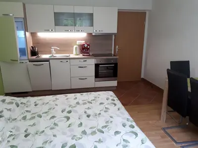 a kitchen with white cabinets and a sink and a table at House Utrinek with free play room, jacuzzy and garage in Podbrdo
