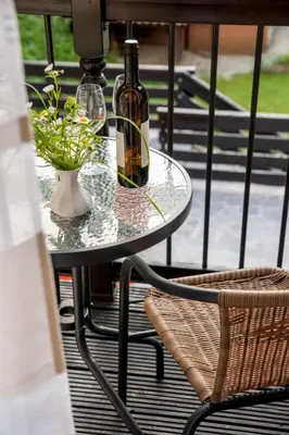 a glass table with two bottles and a vase with flowers at House Utrinek with free play room, jacuzzy and garage in Podbrdo