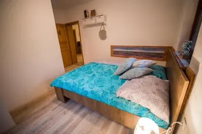a bedroom with a bed with blue sheets and pillows at Guest House Frata in Dvor