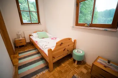 a small bedroom with a bed and two windows at Guest House Frata in Dvor