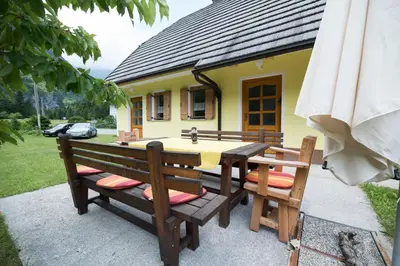 a table and chairs in front of a yellow house at Yellow house in Trenta