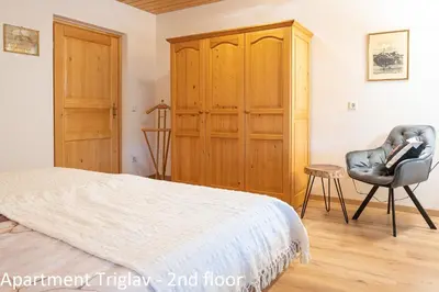 a bedroom with a bed and a chair and a cabinet at Apartments Artemida in Bled