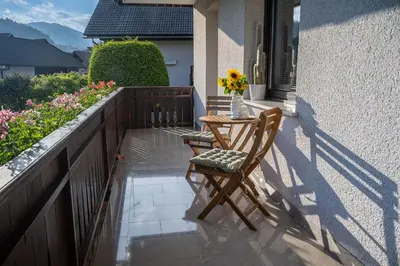 a table and chair on a balcony with a vase of flowers at Apartments Artemida in Bled
