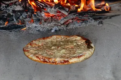 a pizza is cooking in front of a fire at Apartment Micnek Bled in Bled
