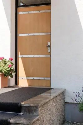 a wooden door of a house with flowers in front of it at Rožna Dolina Apartment in Ljubljana