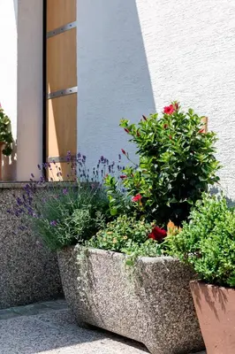 a large stone planter with flowers in front of a building at Rožna Dolina Apartment in Ljubljana