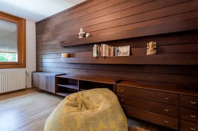 a room with a wooden wall with a chair and a desk at Rožna Dolina Apartment in Ljubljana