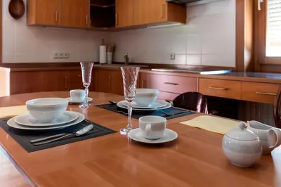 a kitchen with a wooden table with plates and cups at Rožna Dolina Apartment in Ljubljana