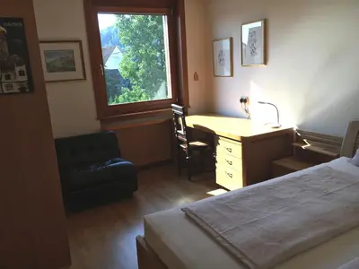a bedroom with a bed and a desk and a window at Rožna Dolina Apartment in Ljubljana