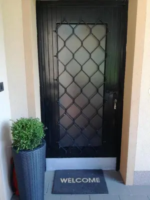 a black door with a potted plant and a welcome mat at Apartma Karavanke in Hrušica