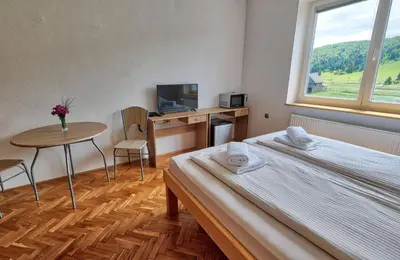 a bedroom with a bed and a desk and a window at Prenočišča Miklavčič in Nova Vas